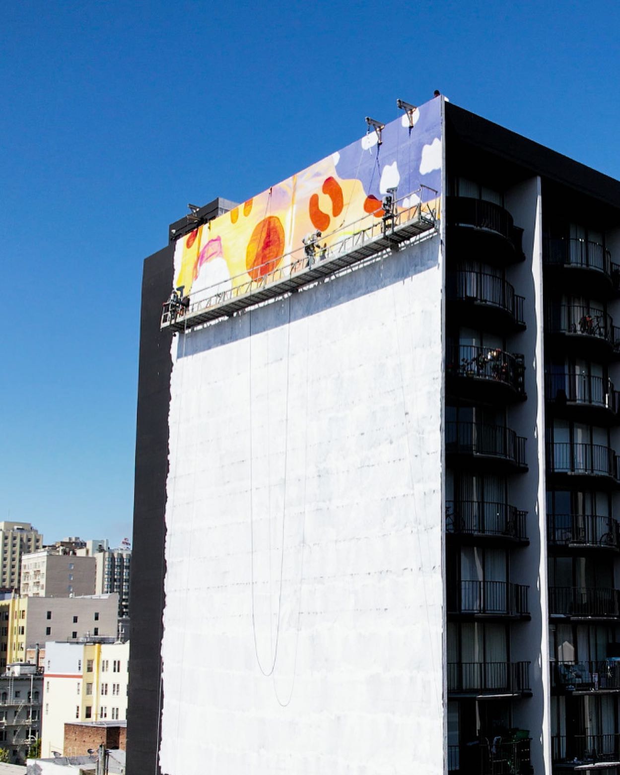 Hoist Media crew on suspended scaffold beginning large-scale mural production on San Francisco building exterior
