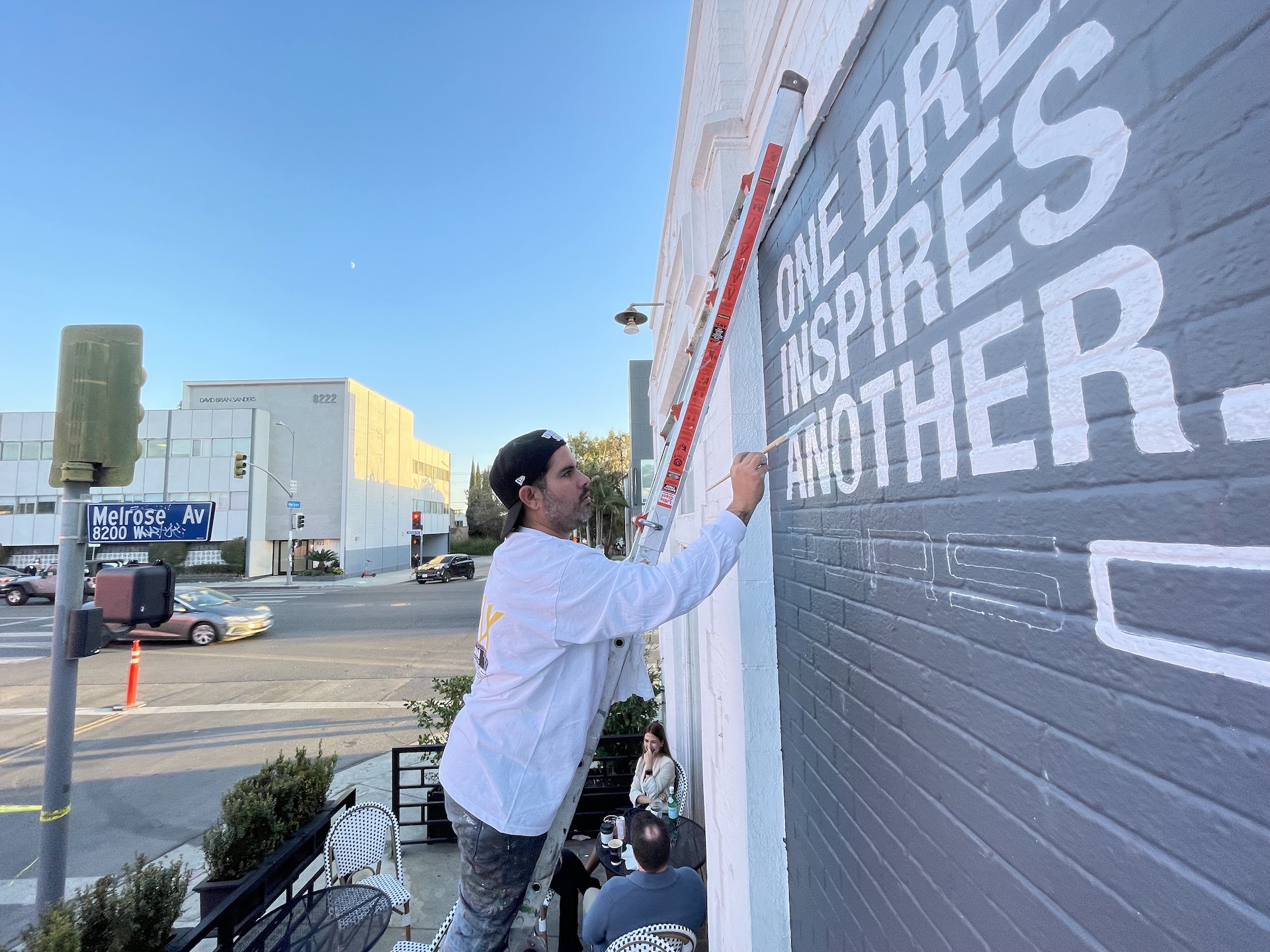 Hoist Media artist on ladder painting Porsche campaign lettering on brick wall on Melrose Avenue West Hollywood