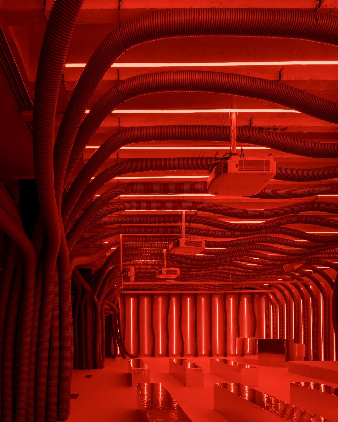 Wide view of Mahou Beer experiential activation looking down tunnel of red corrugated hoses and neon light strips