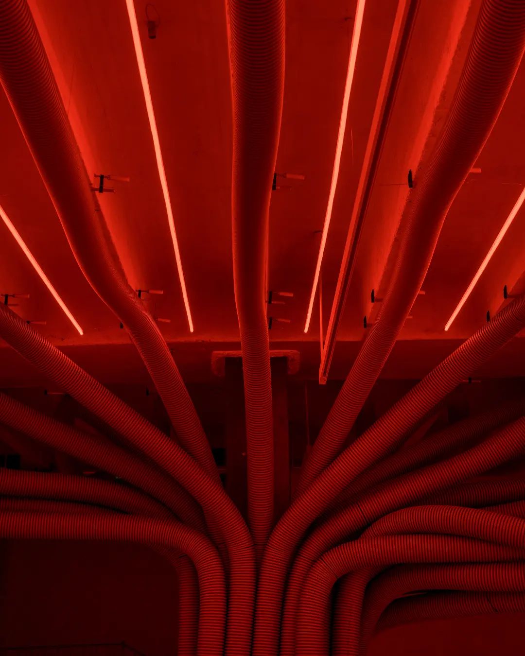 Close-up detail of red corrugated hoses fanning from central column in Mahou Beer spatial design installation Madrid