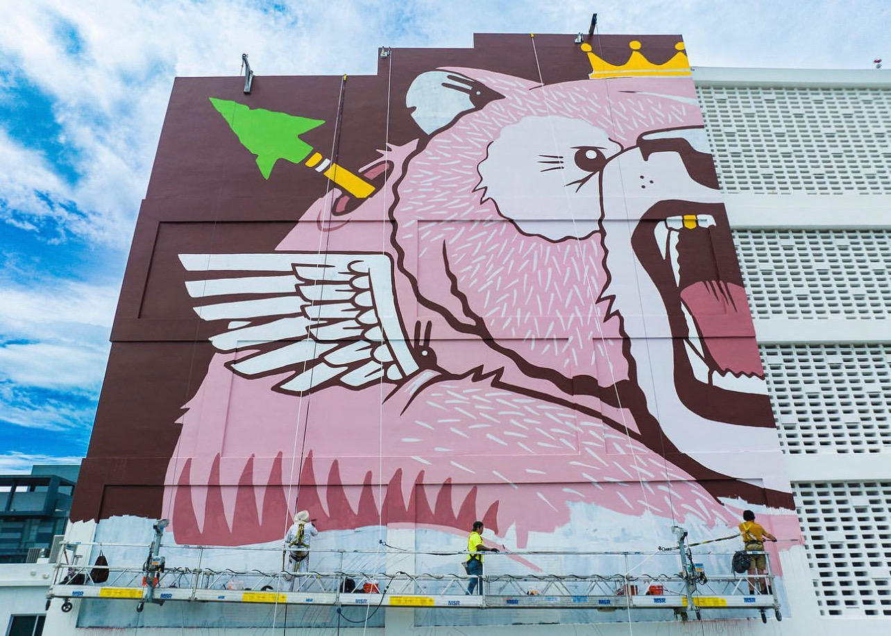 Wide view of New Balance branded mural on Miami parking garage being painted by muralists