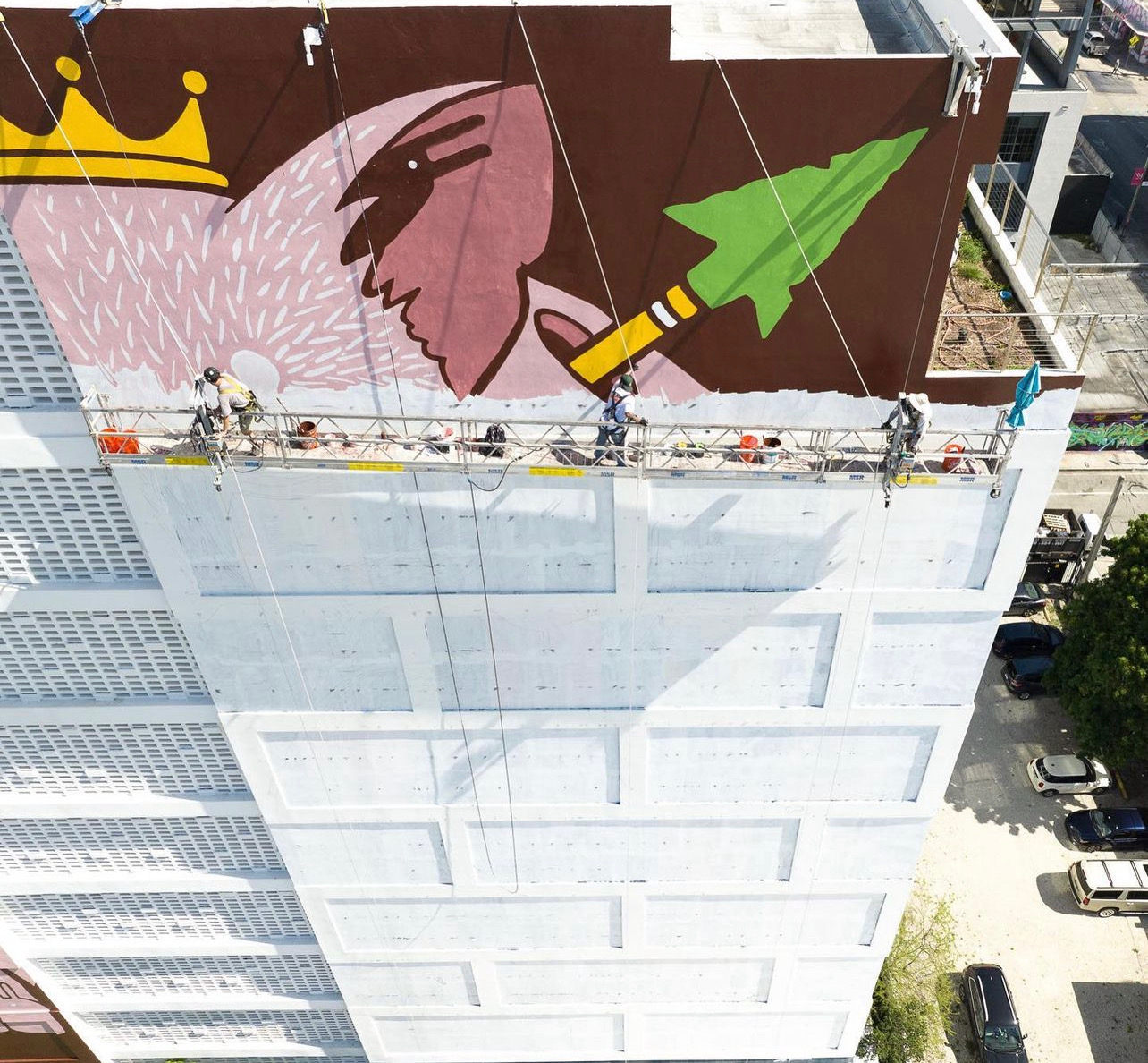 Hoist Media muralists painting New Balance campaign mural on parking garage in Miami